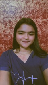 “Young woman smiling in front of a textured red wall, representing a professional in digital marketing services.”