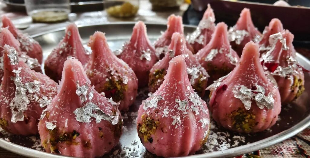 Delicious Gulkand Mawa Modak filled with rich gulkand and topped with pistachios and edible silver leaf.